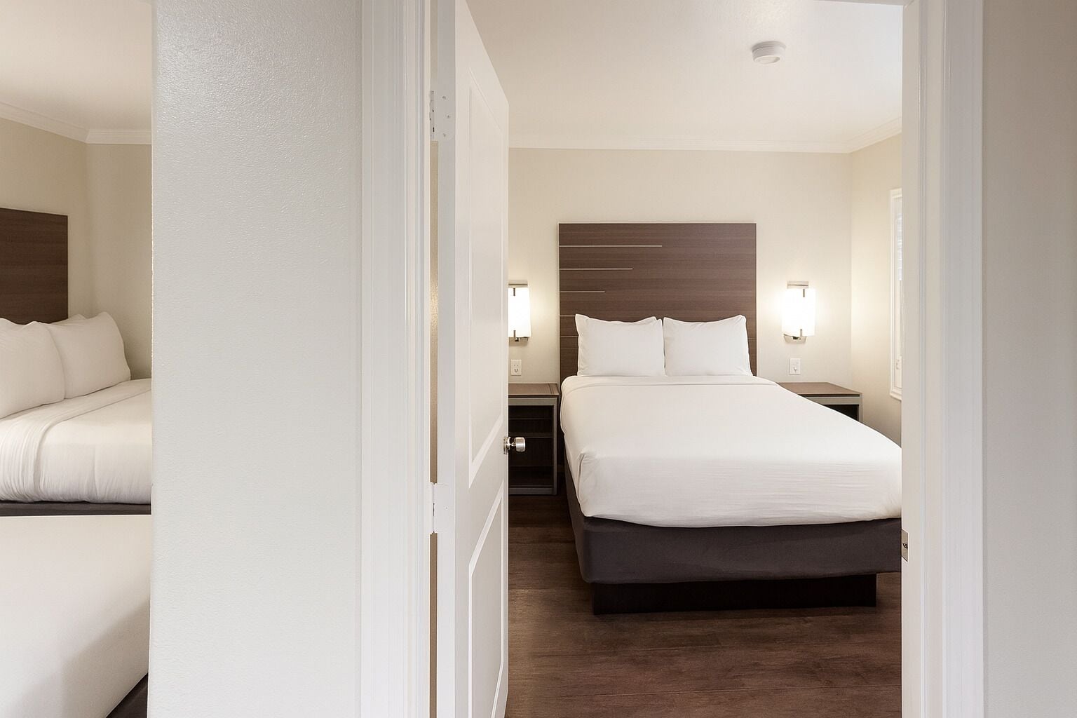 Hotellihuone, jossa on sänky, yöpöydät ja yöpöytälamppu.