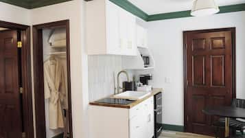 A compact kitchen with a sink, cabinets, and a coffee maker.