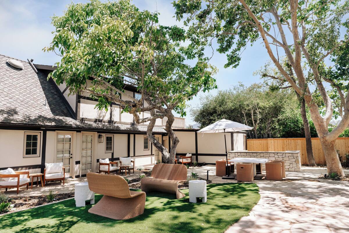 Un patio trasero con mobiliario exterior, un muro de piedra y una valla de madera.