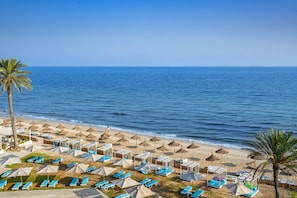 A beach with rows of sun loungers and umbrellas, a palm tree, and the ocean. - Club Sunshine Rosa Rivage - All inclusive (Monastir)