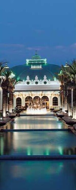 Un edificio grande con una cúpula y una piscina frente a él.