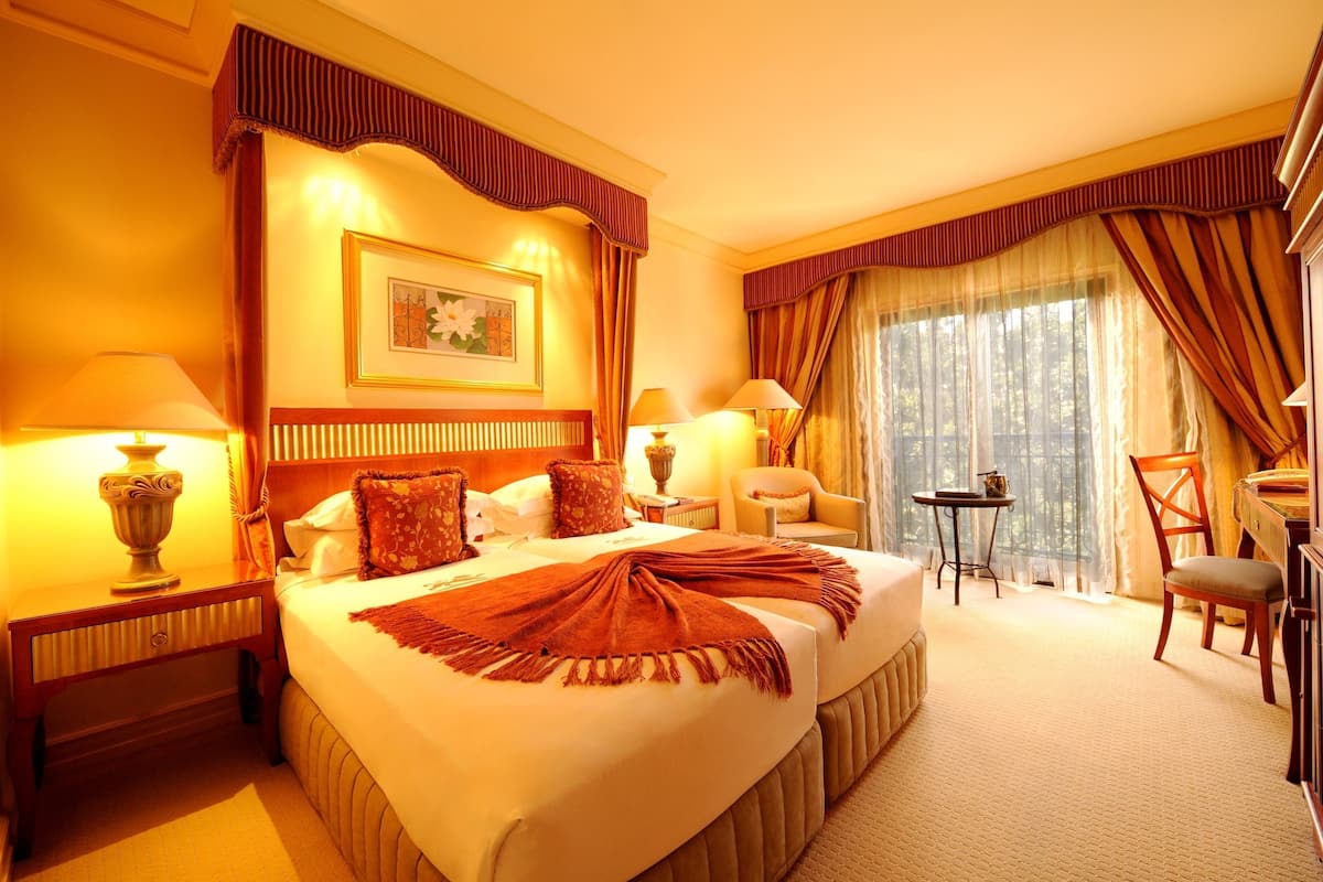 A hotel room with a large bed, two bedside tables, a desk, and a chair.