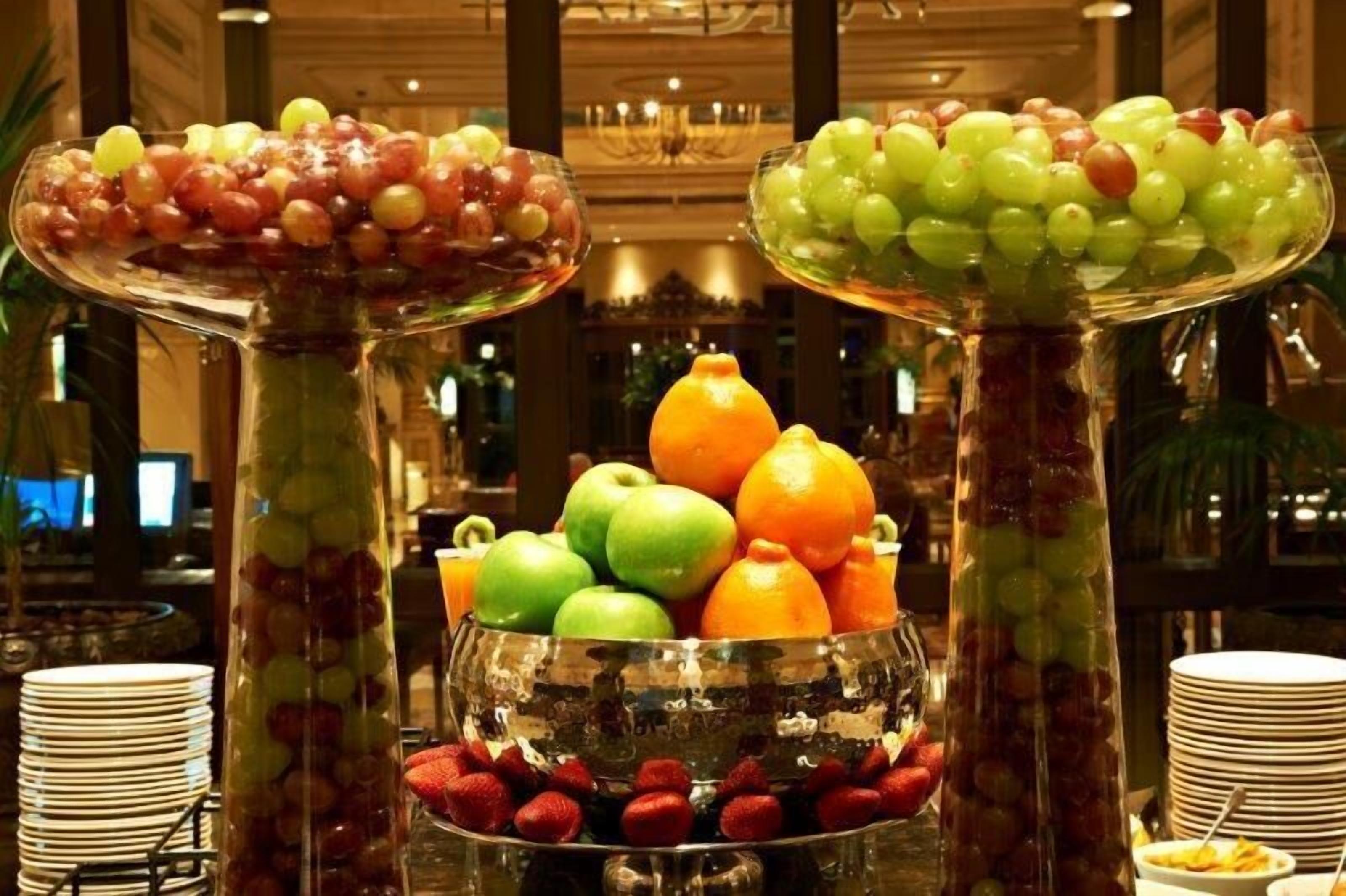 A buffet with various fruits and vegetables displayed in clear glass containers.