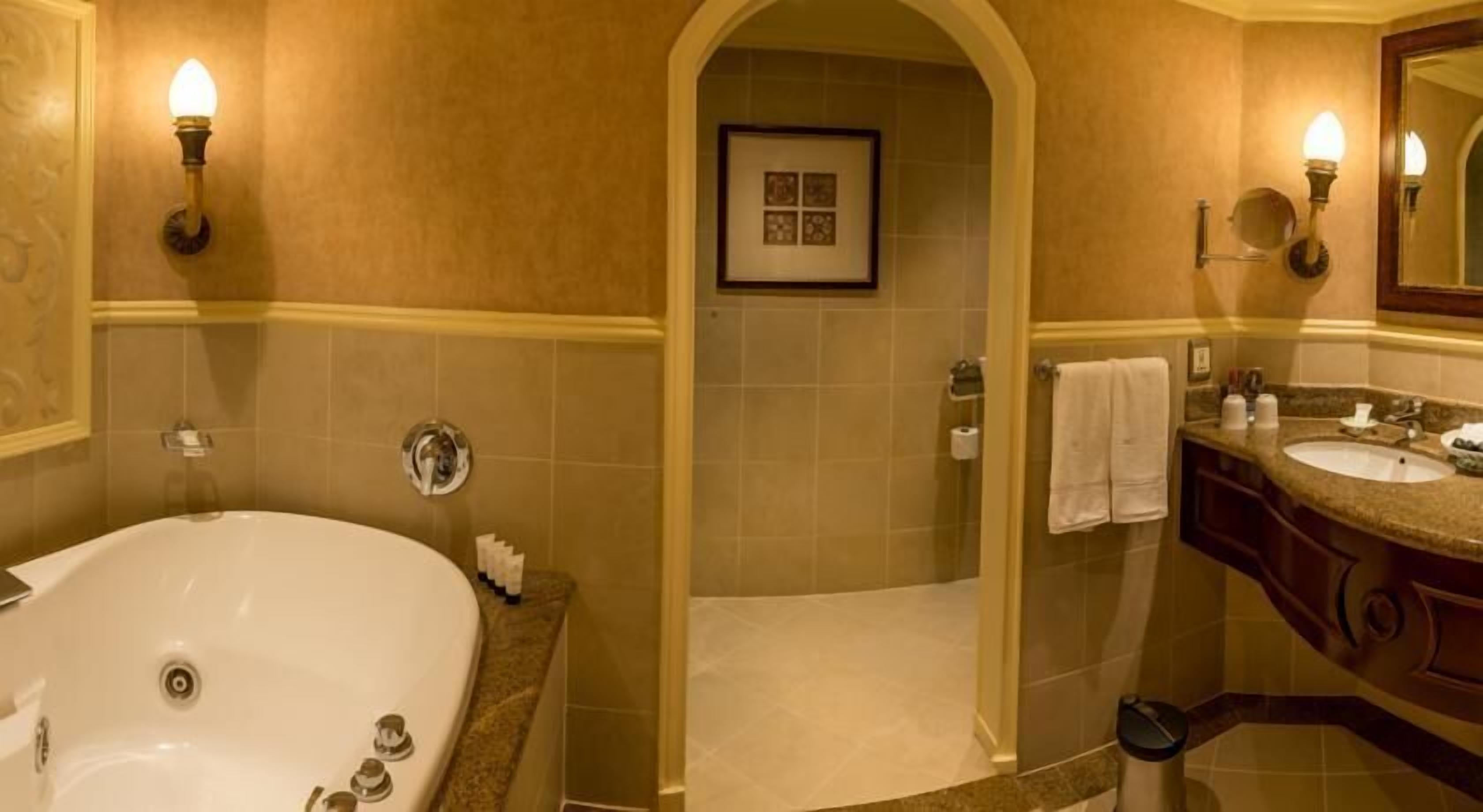 A bathroom with a large bathtub, a shower area, and a vanity with a sink and mirror.