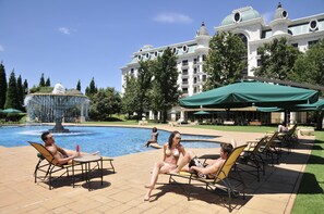 Área de piscina com espreguiçadeiras e uma fonte.