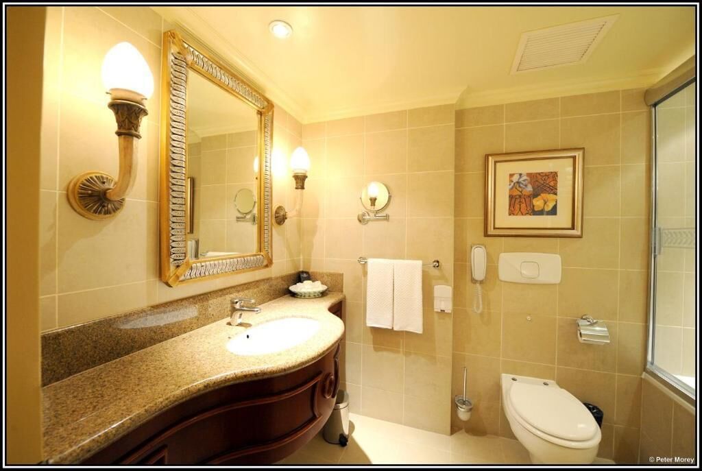 A bathroom with a large mirror, a sink, a toilet, and a shower.