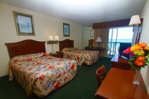 Ein Hotelzimmer mit zwei Betten, einem Schreibtisch, einem Stuhl, einer Lampe und einem Fenster mit Blick.