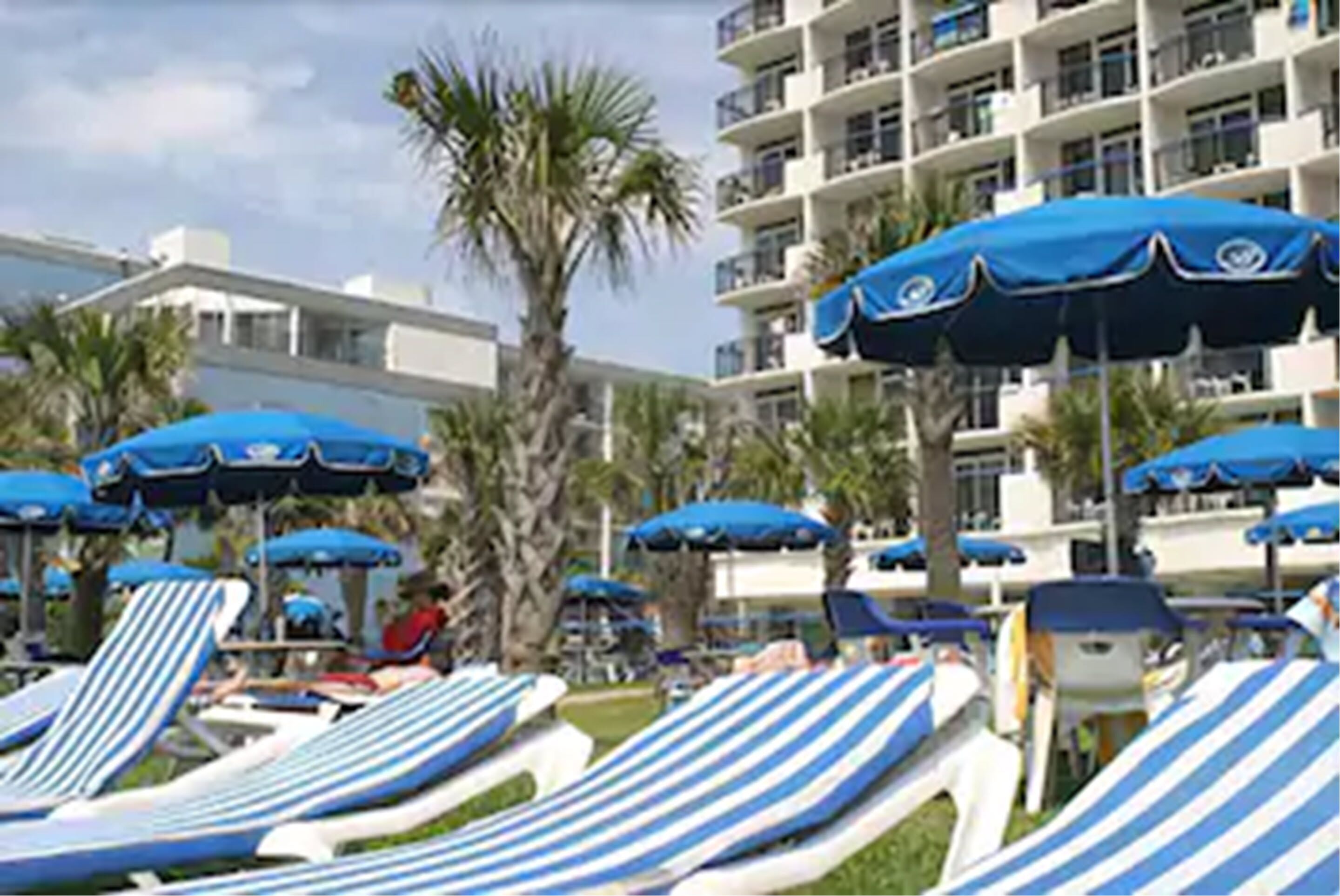 A poolside area with striped lounge chairs and blue umbrellas.