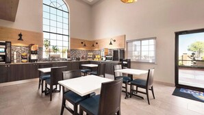 A modern restaurant with high ceilings, large windows, and a mix of dark and light wood paneling. Tables and chairs are arranged for dining.