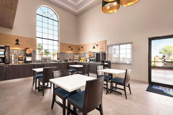 A modern restaurant with high ceilings, large windows, and a mix of dark and light wood paneling. Tables and chairs are arranged for dining. - Days Inn & Suites by Wyndham Houston Hobby Airport (Houston)