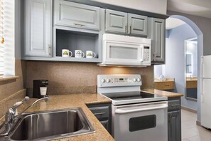 A kitchen with granite countertops, stainless steel appliances, and light blue cabinetry. - Days Inn & Suites by Wyndham Houston Hobby Airport (Houston)