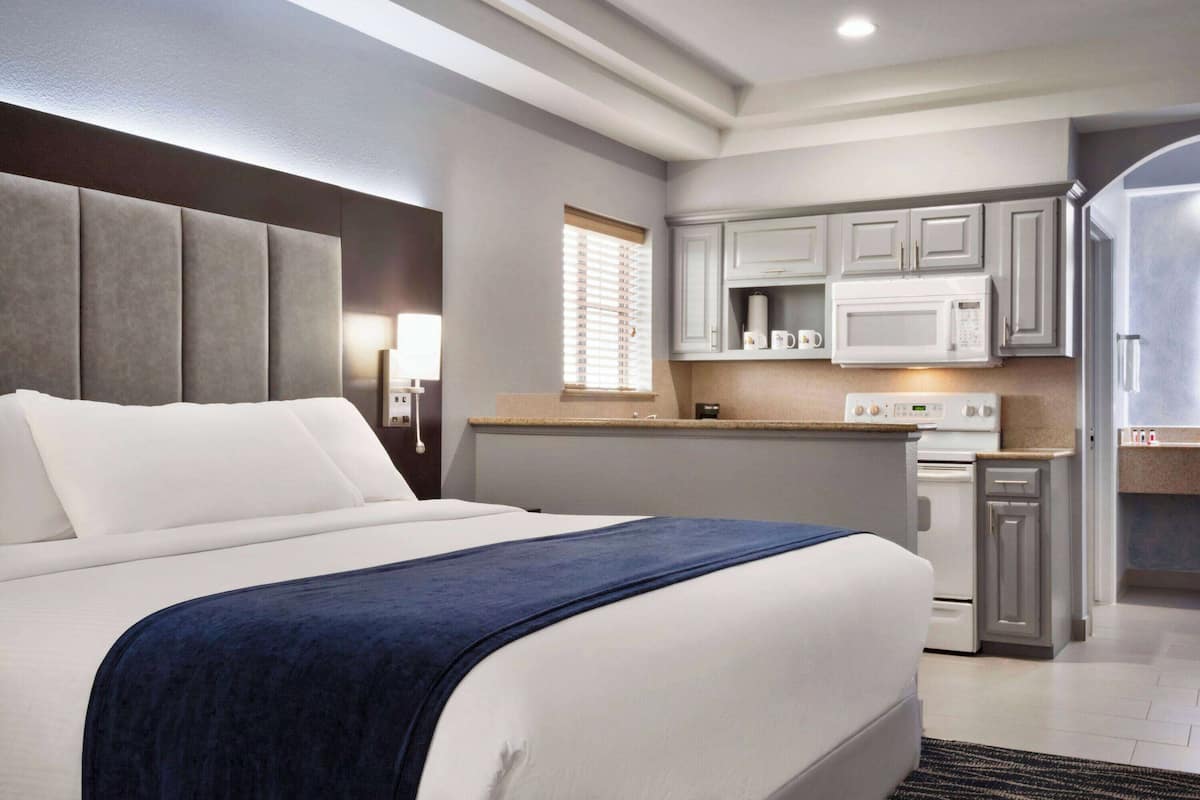 Une chambre d’hôtel équipée d’un lit, d’un bureau, d’un four à micro-ondes et d’une petite kitchenette.