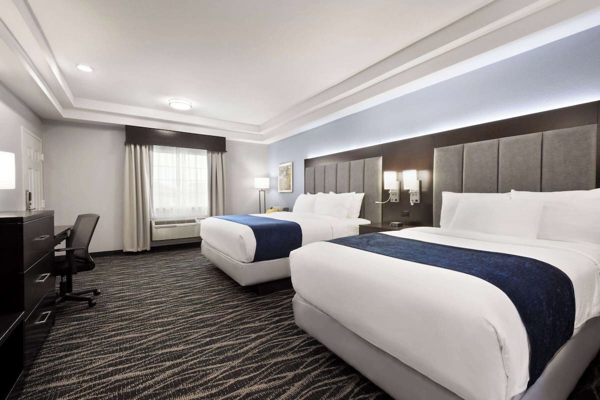 Une chambre d’hôtel avec deux lits, un bureau et une chaise.