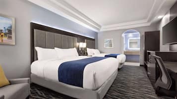 A hotel room with a large bed, a desk, a chair, a TV, and a bathroom visible through an archway.