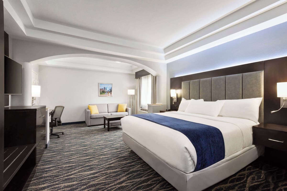 Une chambre d’hôtel avec un grand lit, un bureau, une chaise et un téléviseur.