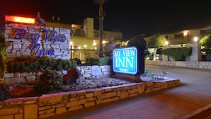 L’entrée d’un hôtel avec une façade en pierre, un panneau néon indiquant « complet » et un panneau lumineux indiquant « Bay View Inn ».