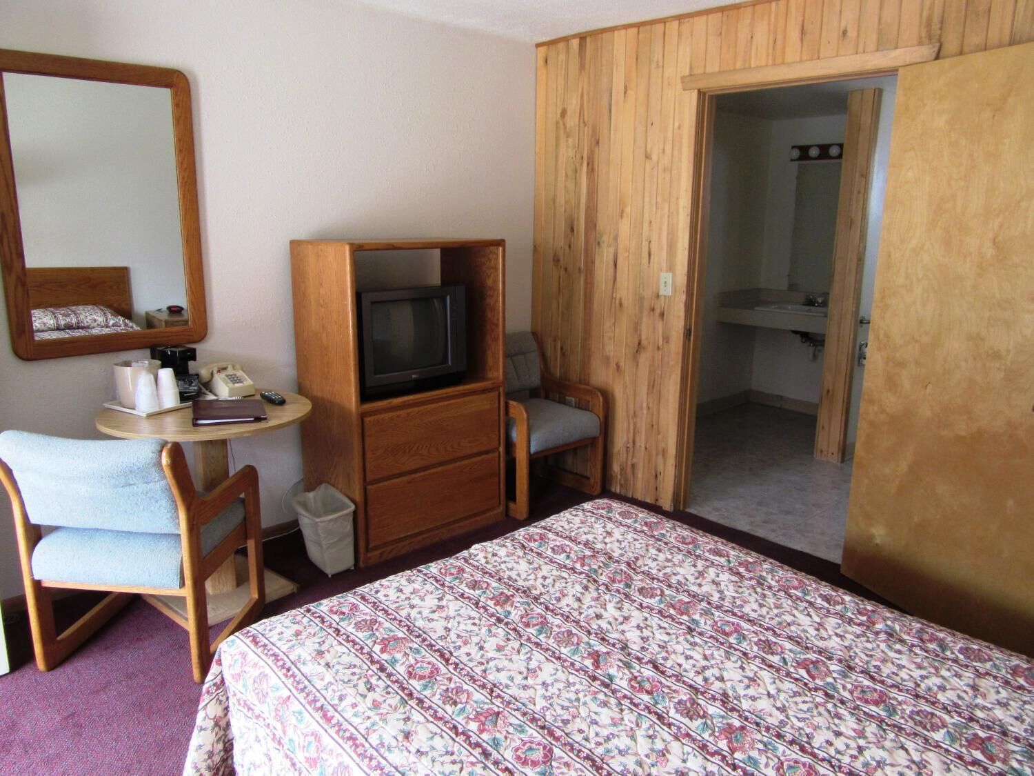 Une chambre d’hôtel comprenant un lit, un bureau avec un téléphone, une télévision et une chaise.
