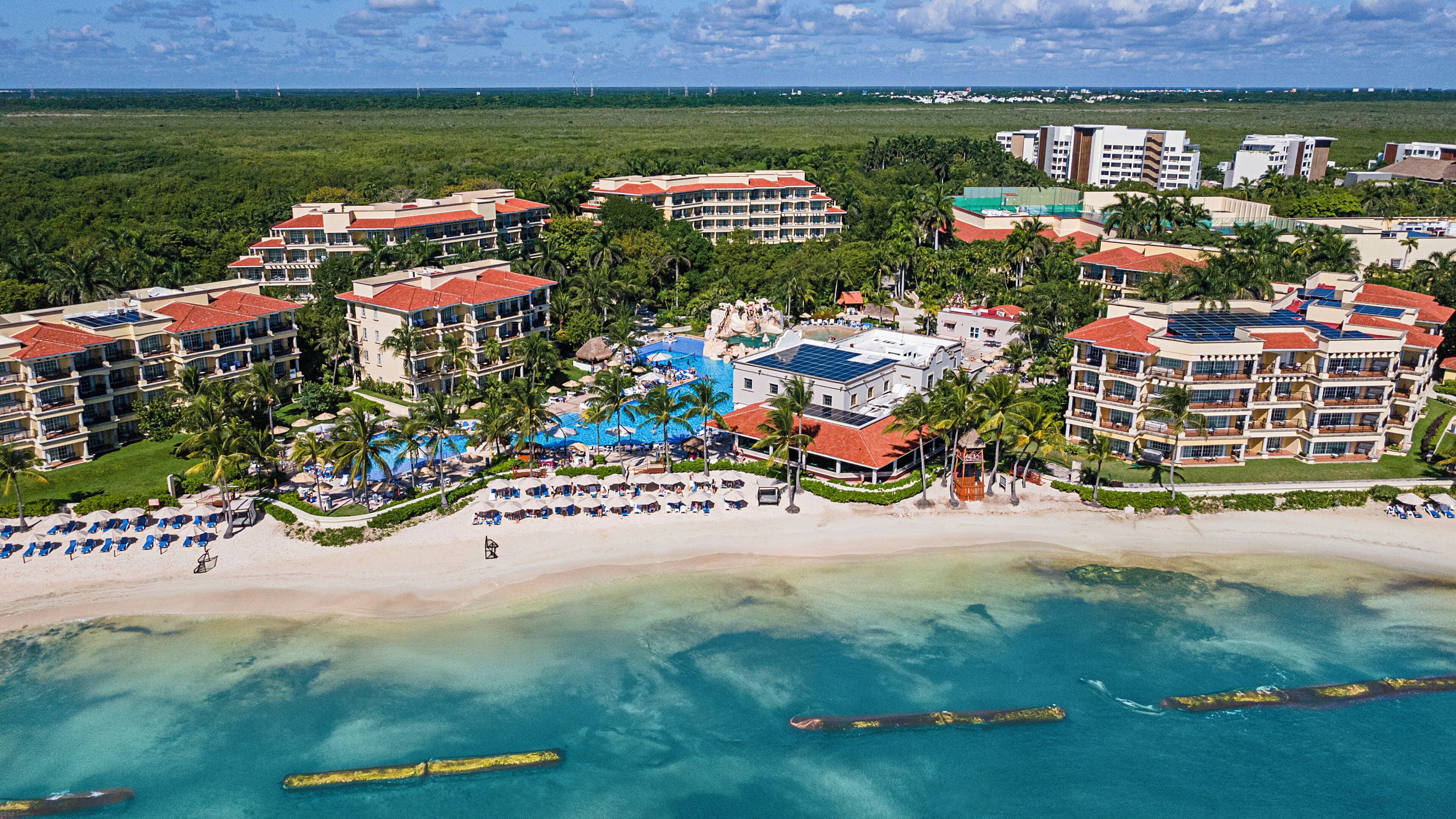 A resort with multiple hotel buildings, a central pool area, and a beach.
