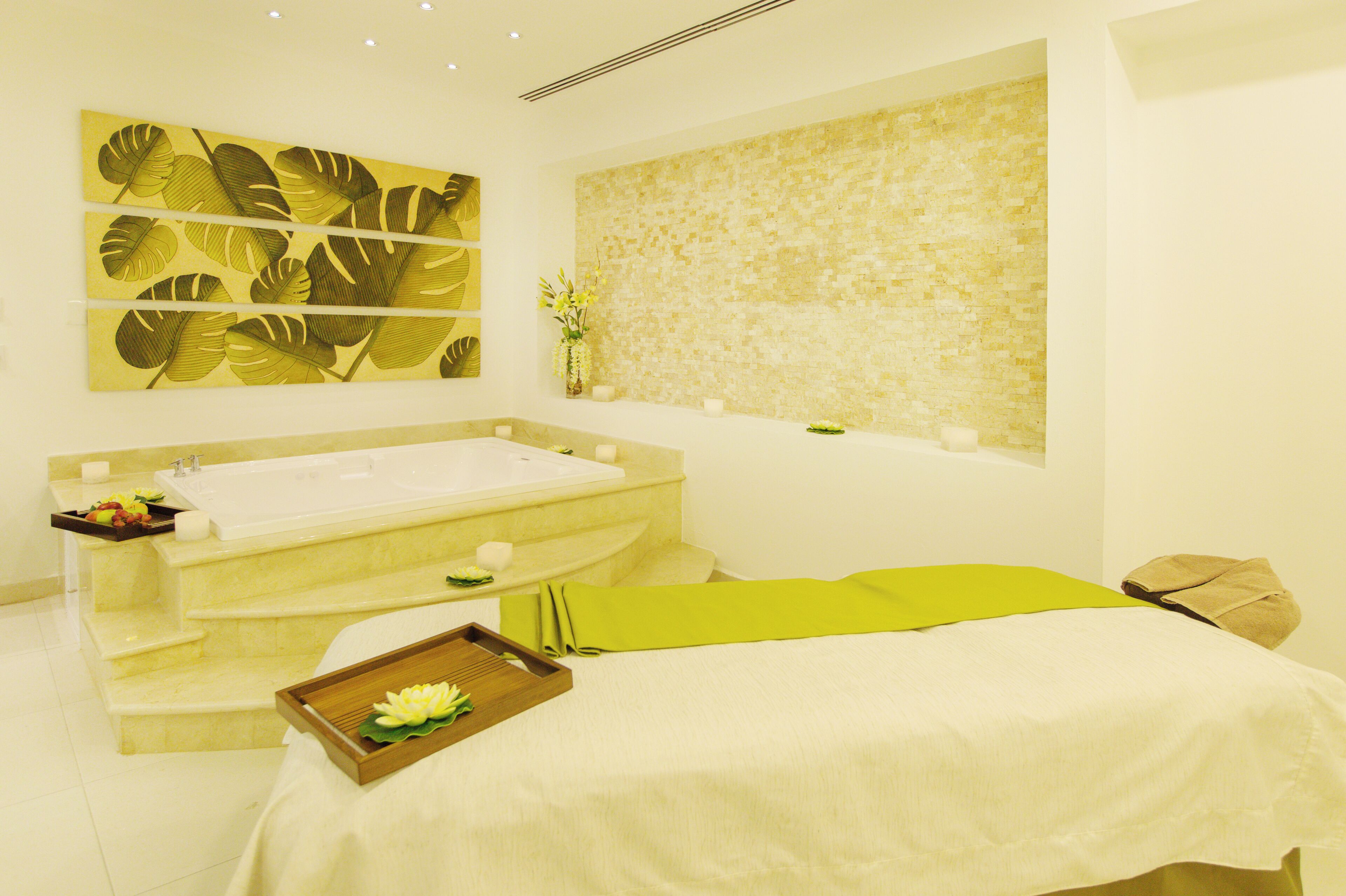A modern spa room with a large bathtub, a massage table, and a wall-mounted artwork.