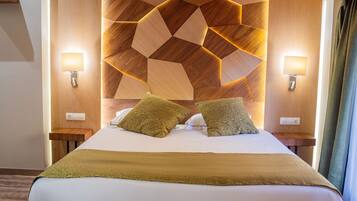 A hotel room with a geometric-patterned headboard, two bedside lamps, and two decorative pillows.