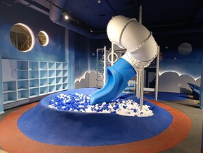 A play area with a blue slide, white and blue balls, and a blue carpet. - Hotel Spa Princesa Parc (Arinsal)