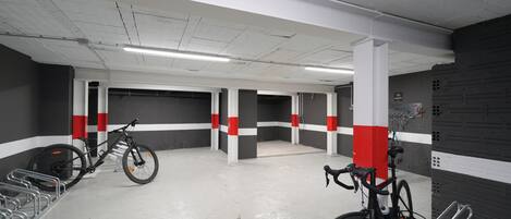 A parking garage with bicycles, concrete pillars, and a white and red color scheme.