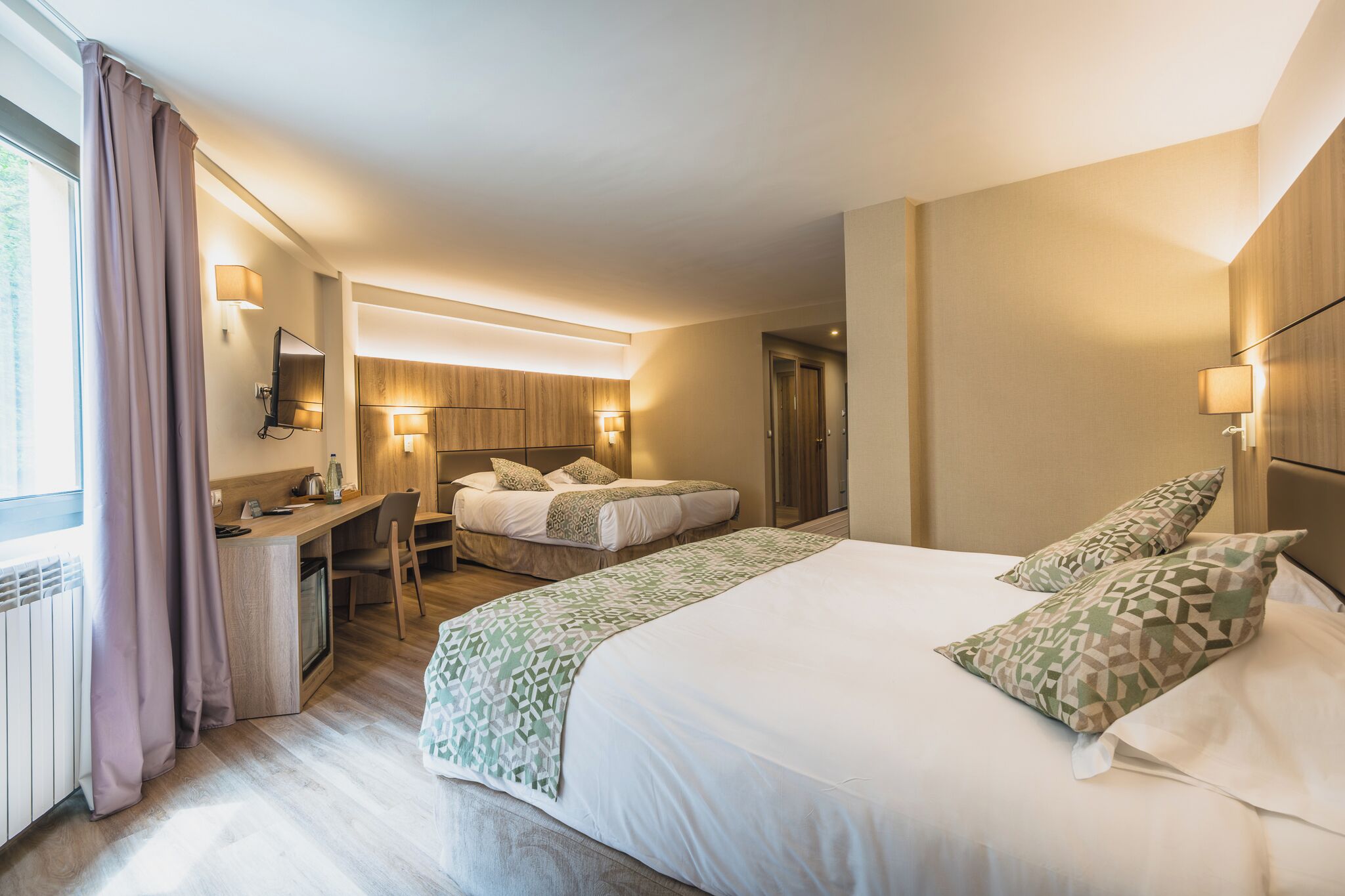 Une chambre d’hôtel avec un grand lit, un bureau, une chaise, un miroir et une armoire.
