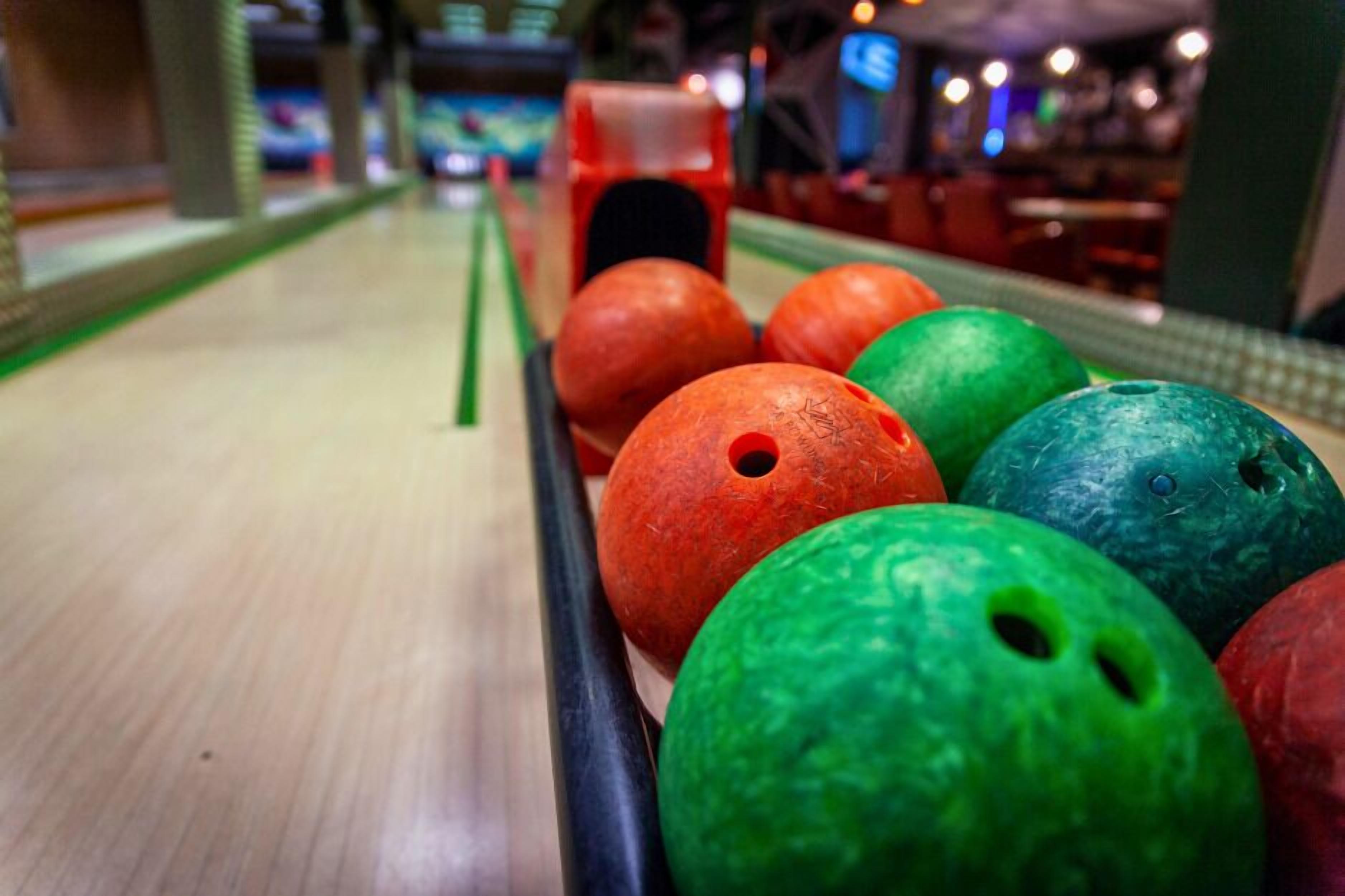 A bowling alley with a lane and a rack of colorful bowling balls.