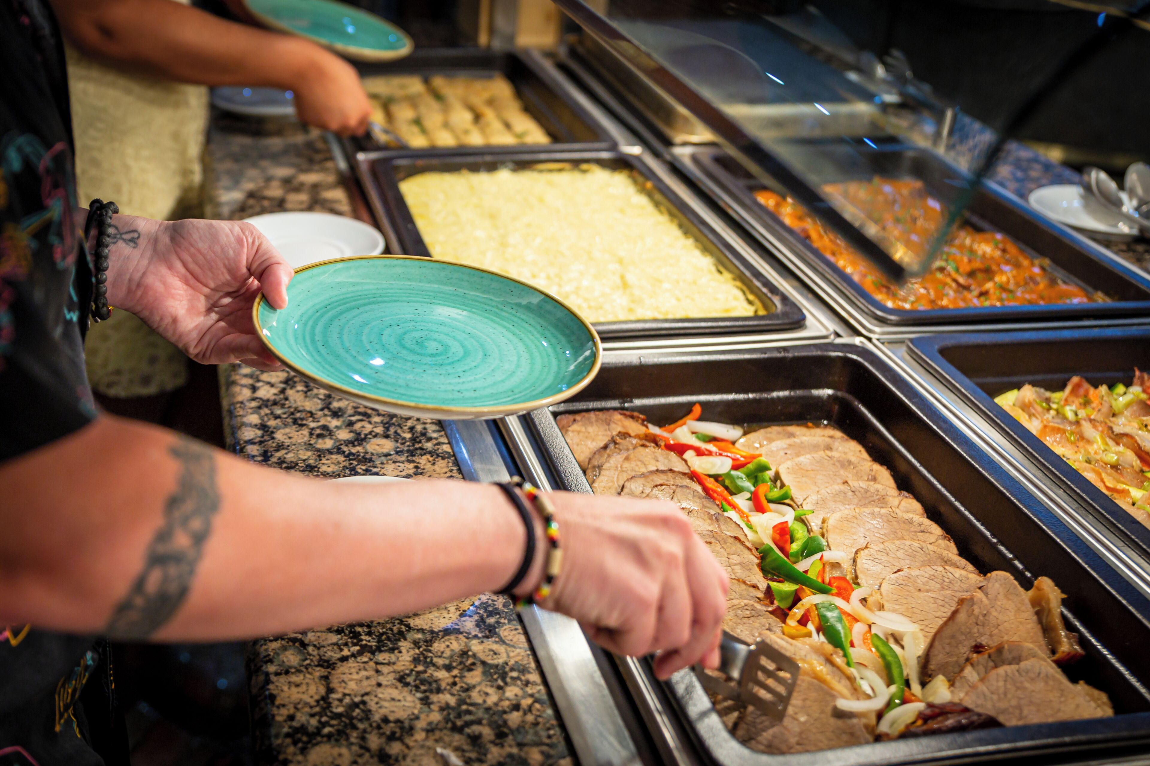 A buffet with various food options, including sliced meats and vegetables.