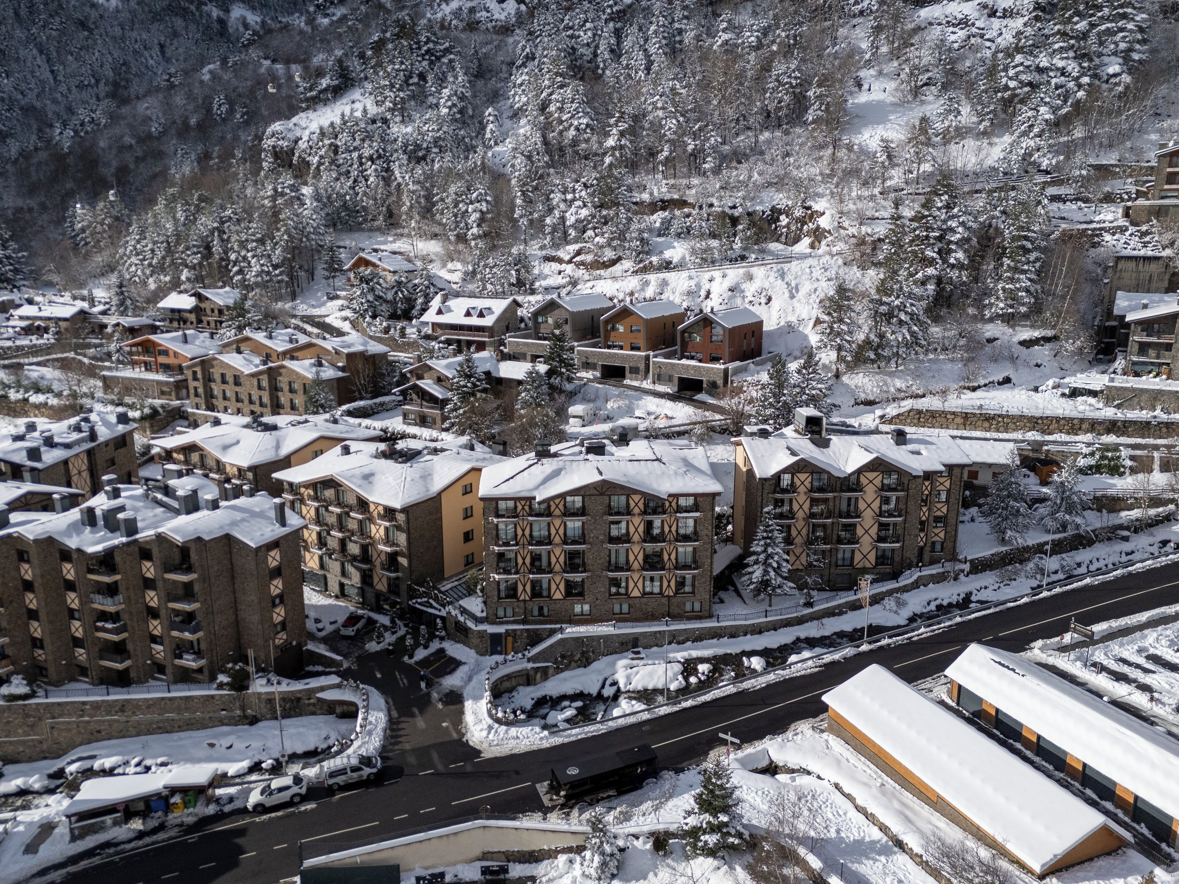 A snow-covered resort with multiple buildings, roads, and a mountain backdrop.