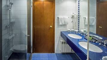 Ein Badezimmer mit Dusche, zwei Waschbecken, einem Spiegel und einer Tür.