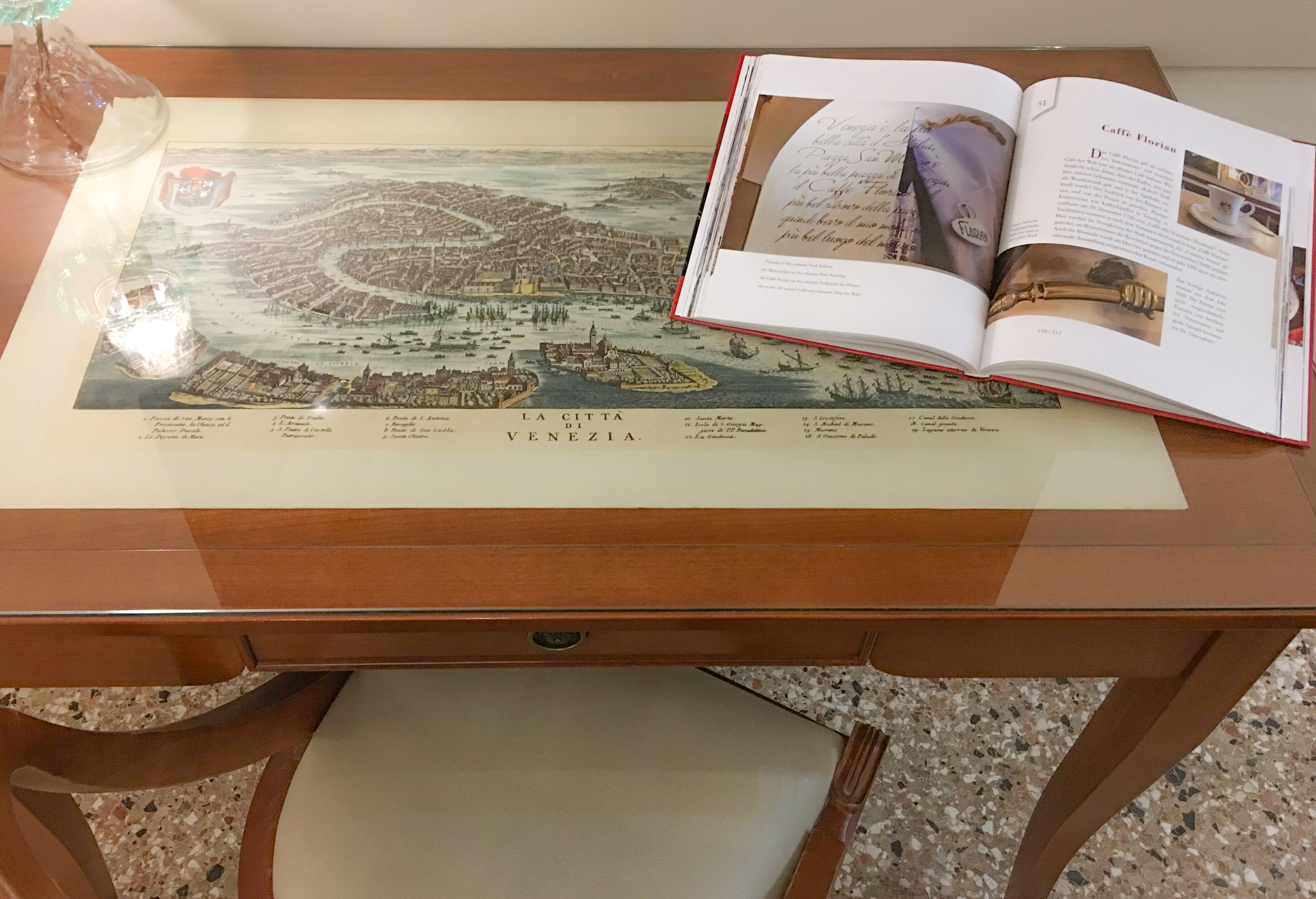 Un libro abierto mostrando un mapa de Venecia y otra página con texto e imágenes.