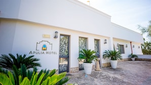 The exterior of Apulia Hotel with a modern design, featuring large potted plants and a clean, white facade. - Città Bianca Country Resort (Ostuni)