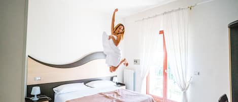 Un dormitorio con cama, mesita de noche, lámpara y ventana con cortinas.