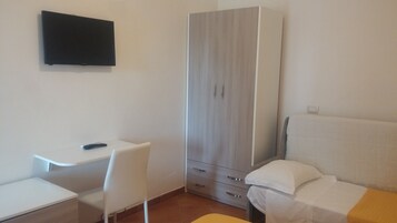 Egy kis, rendezett szoba, amelyben egy ágy, egy íróasztal és egy szekrény található.
