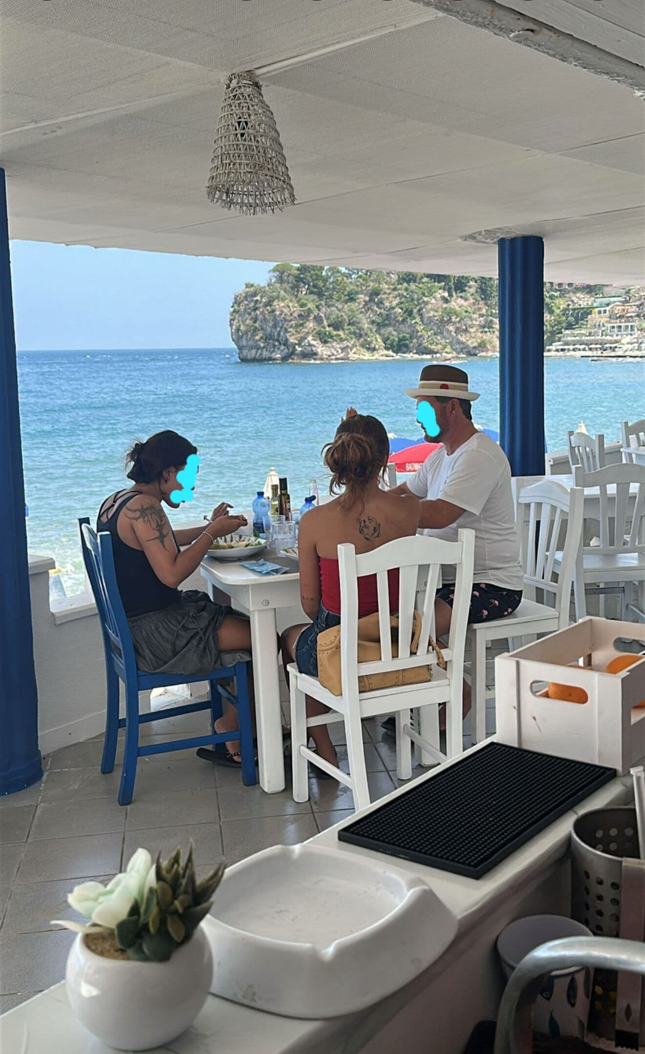 Un restaurante frente al mar con mobiliario blanco y vistas al océano.