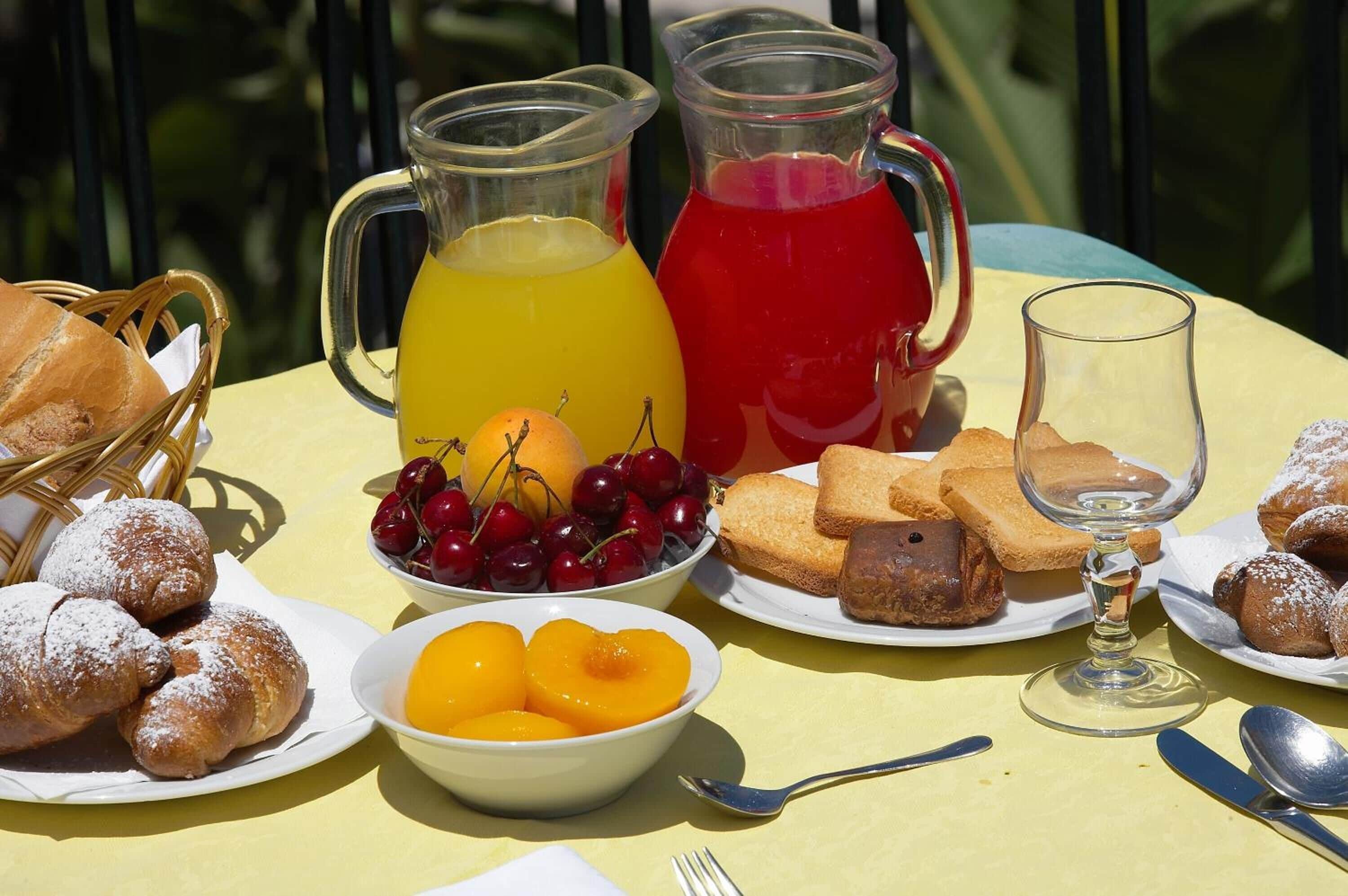 A table set with breakfast items including pastries, fruit, and beverages.