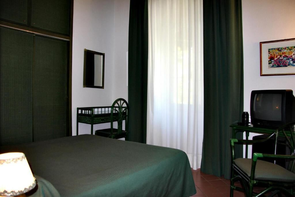 A hotel room with a bed, a chair, a television, and a lamp.