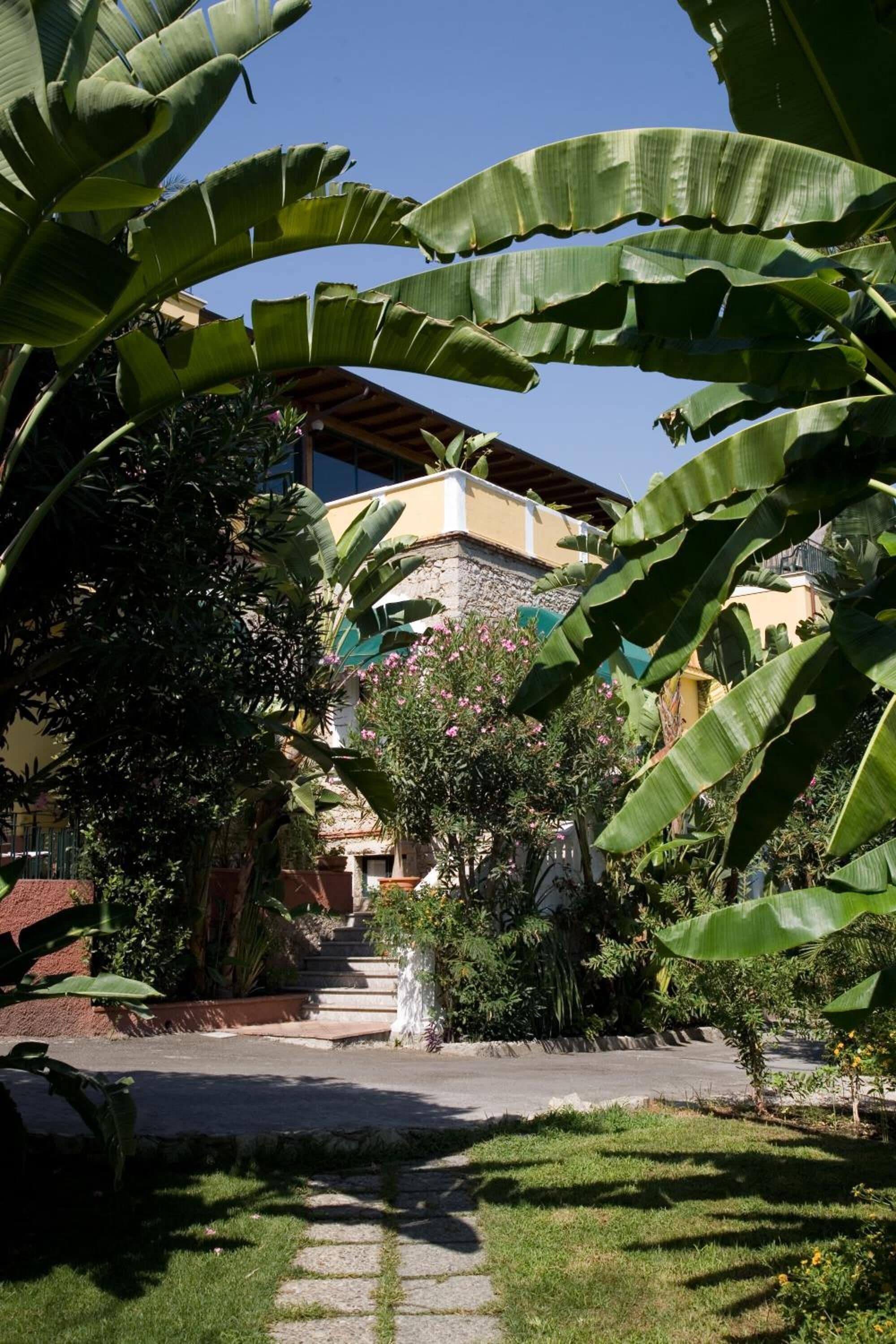 Un sendero en un jardín que lleva a un edificio con fachada de piedra y techo de tejas.