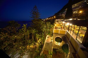 Ein Hotel mit Terrasse mit Blick auf einen Strand, das Sitzmöglichkeiten im Freien und einen Poolbereich bietet.
