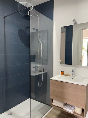 Ein modernes Badezimmer mit einer Duschkabine aus Glas, einem weißen Waschbecken und einem Holzlagerplatz.