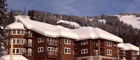 Et hotel med flere etager, træfacade, flere balkoner og et tag dækket af sne.