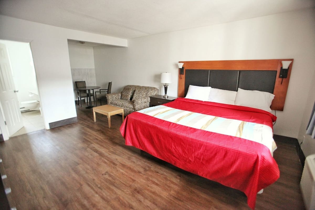 Ein Hotelzimmer mit Bett, Stuhl, kleinem Tisch und Schreibtisch.