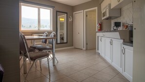 A kitchen with white cabinets, a dining area with a table and chairs, and a view through a window.