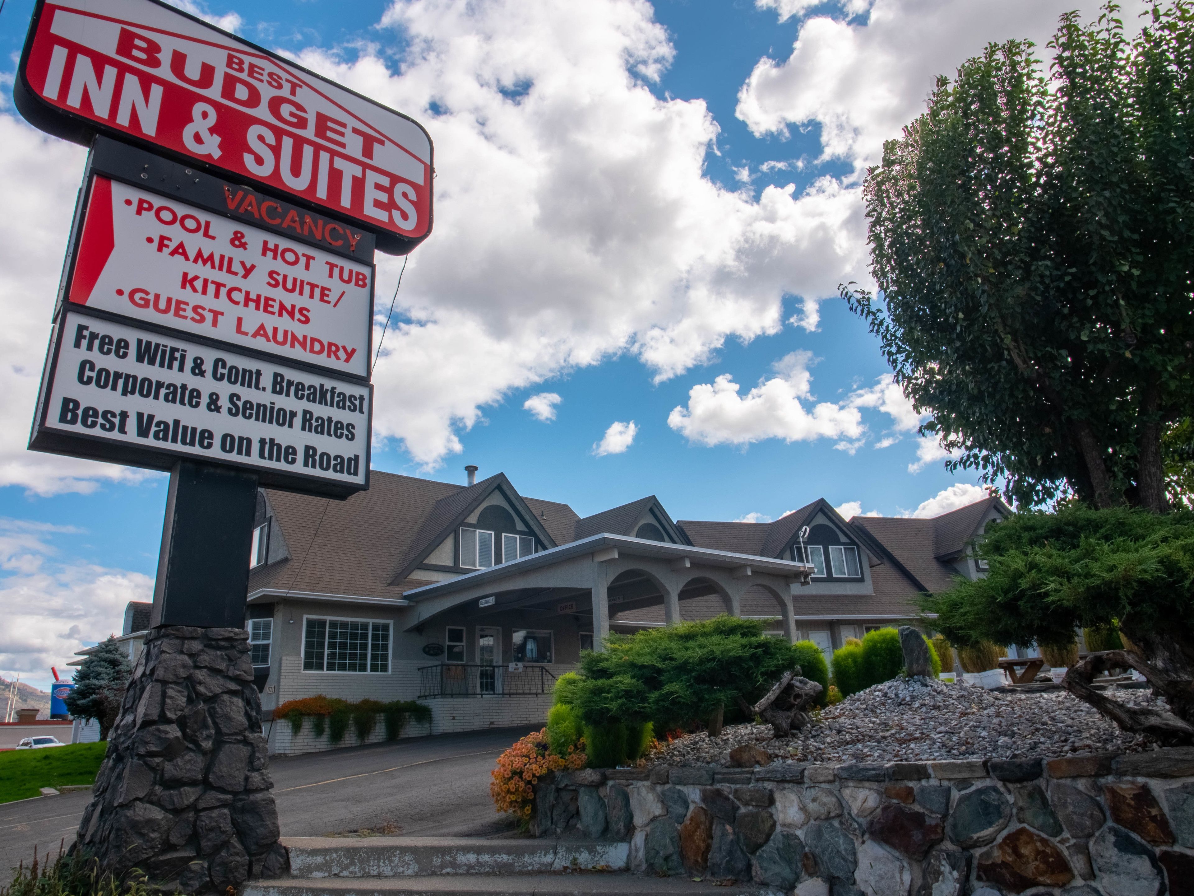A sign for a budget inn & suites with amenities like pool, hot tub, family suite, guest laundry, free WiFi, corporate breakfast, and senior rates.