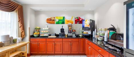 A modern kitchen with orange cabinets, a wooden table, and various appliances.