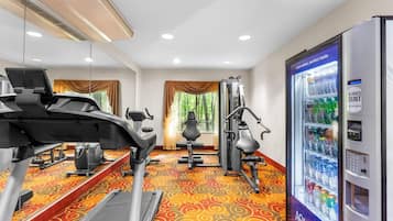Ein Fitnessraum eines Hotels mit Trainingsgeräten, einem Wasserspender und gemustertem Teppichboden.