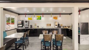 A modern kitchen with a central island, black cabinets, and a seating area with a table and chairs. - Quality Inn Madisonville (Madisonville)
