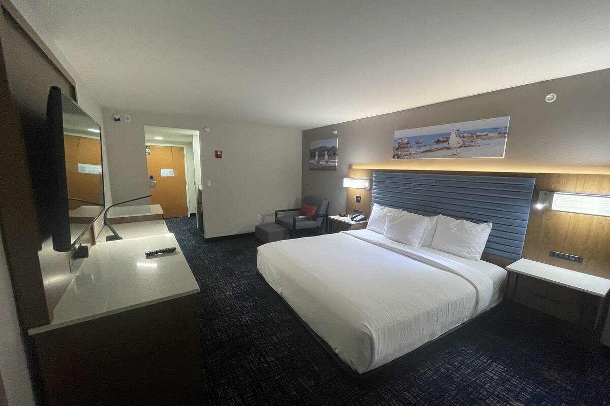 Une chambre d’hôtel avec un grand lit, un bureau, une chaise, une télévision et un tableau au mur.
