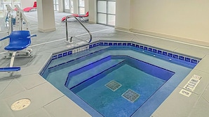 An indoor swimming pool with a blue tiled edge, a diving board, and a lifeguard chair. - Wingate by Wyndham Panama City Area Lynn Haven (Lynn Haven)